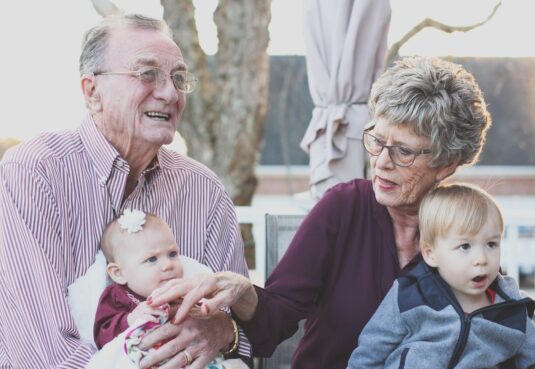 Grandmother and Grandfather Holding Child on Their Lap