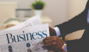 person wearing suit reading business newspaper