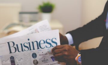 person wearing suit reading business newspaper