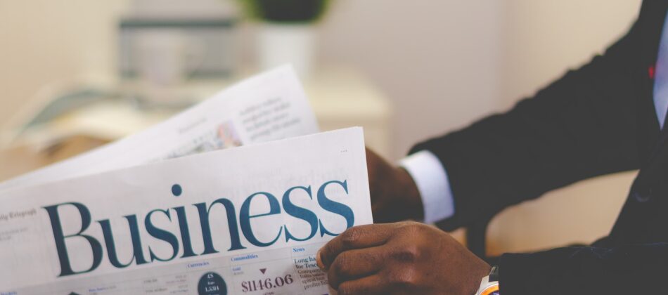 person wearing suit reading business newspaper